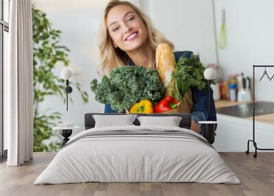 Beautiful young woman grocery shopping bag with vegetables at home. Wall mural