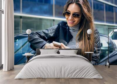 beautiful young woman using her mobile phone in the car. Wall mural