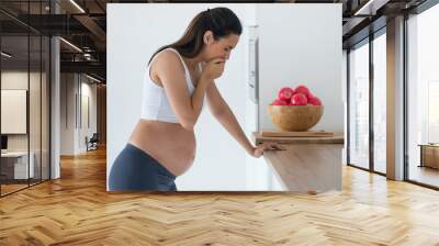 Disgusted pregnant young woman suffering with nausea in morning at home. Wall mural