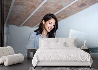 Elegant young business woman receiving a phone message while working with computer in the office. Wall mural