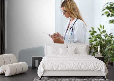 Female doctor working with laptop and researching some medication information in the consultation. Wall mural