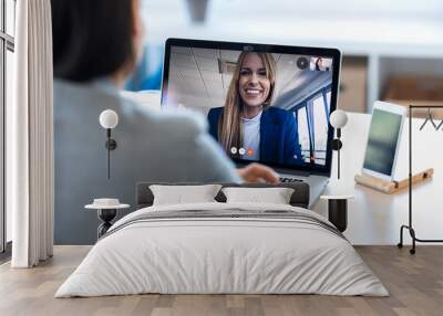 Female employee speaking on video call with her colleague on online briefing with laptop at home. Wall mural