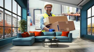 Handosme worker holding cardboard boxes while looking at camera in store warehouse Wall mural