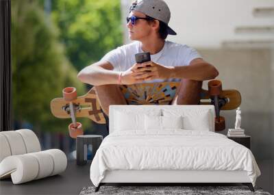 handsome skater boy using his mobile phone in the street. Wall mural