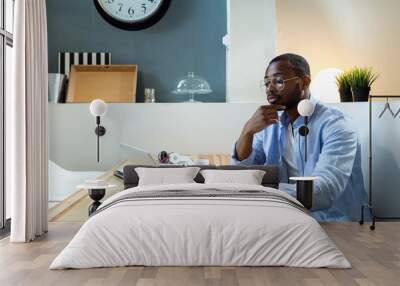 Handsome young black man working with laptop at home. Wall mural