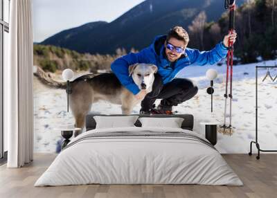 Handsome young man with his dog over winter background. Wall mural