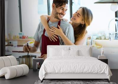 Happy young couple cooking together in the kitchen at home. Wall mural