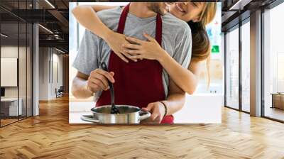 Happy young couple cooking together in the kitchen at home. Wall mural