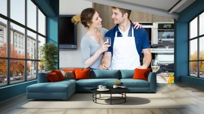 Happy young couple cooking together in the kitchen at home. Wall mural