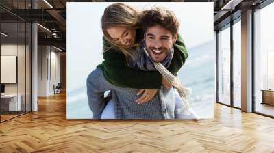 Happy young couple enjoying the day in a cold winter on the beach. Wall mural