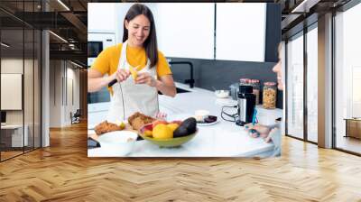 Happy young nutritionist woman peeling fruit to prepare a healthy handmade smoothie in the kitchen at home. Wall mural