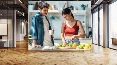 Healthy young woman cutting fresh fruit while cooking healthy food in the kitchen at home. Wall mural