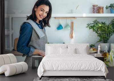 Healthy young woman cutting fresh vegetables while cooking healthy food in the kitchen at home. Wall mural