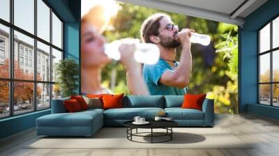 Horticulturist couple having a working break and drinking water in the garden. Wall mural