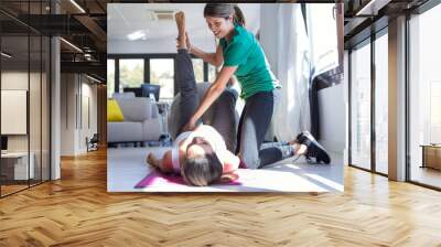 Physiotherapist helping to beautiful pregnant woman for doing pilates exercises with ball preparing for childbirth. Wall mural