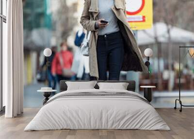 Pretty young woman crossing the street while listen to music with the wireless earphones. Wall mural