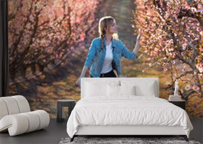 Pretty young woman with a vintage bike looking the cherry blossoms on the field in springtime. Wall mural