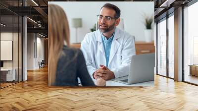 Shot of handsome mature male doctor talking while explaining medical treatment to patient in the consultation. Wall mural