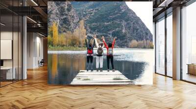 Shot of pretty family looking at the horizon sitting on a pier on the lake Wall mural