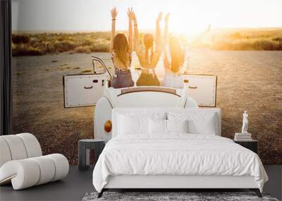 Three pretty young women driving on road trip on beautiful summe Wall mural