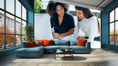 Two attractive business women talking and working with computer and digital tablet in coworking place Wall mural