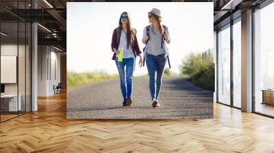 two beautiful ladies hikers walking on the road. Wall mural