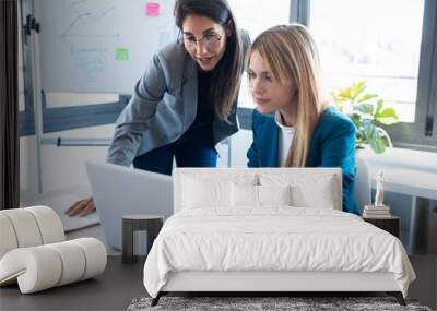 Two business women working together with laptop in the office. Wall mural