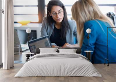 Two business women working together with laptop in the office. Wall mural