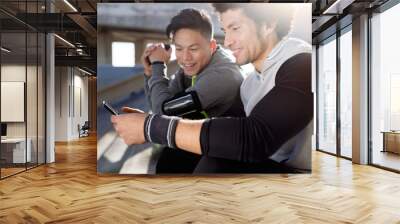 Two fit and sporty youn men using mobile phone in the city. Wall mural