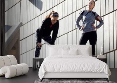 Two fit and sporty young women relaxing after work out in the pa Wall mural