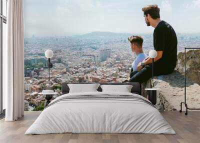 Two young men looking at the views form the top of a mountain. Wall mural