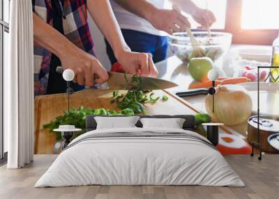 Young couple cooking together in the kitchen at home. Wall mural