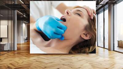 Young physiotherapist doing a face treatment to the patient in a physiotherapy room. Wall mural