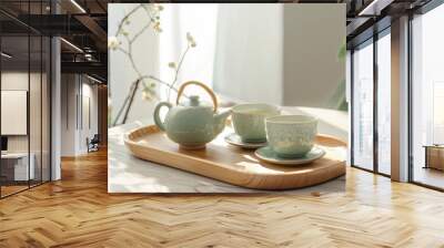 Elegant green ceramic teapot and two matching cups on top, placed on a wooden surface against a white background. Wall mural