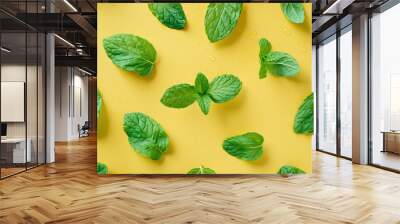 Small mint leaves on a yellow background. Texture for background, wallpaper, poster, banner, card. View from above. Wall mural