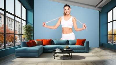 Active happy fit girl with centimeter. Wall mural