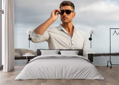 Gorgeous stylish man wearing fashionable shirt and sunglasses. City style. Wall mural