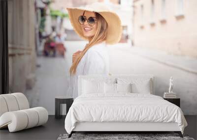 Happy woman on vacation wearing summer hat Wall mural