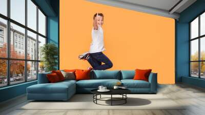 Little boy jumping in the studio, smiling. Wall mural