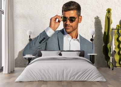 Modern businessman. Confident young man in fashionable suit and sunglasses posing outdoor, relaxing. Wall mural