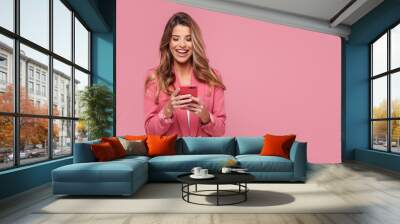 photo of a happy young beautiful woman using mobile phone, smiling, posing isolated over pink pastel Wall mural