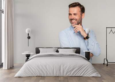 Photo of a smiling formal business man wearing a light blue shirt,  standing and looking at camera Wall mural