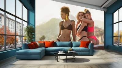 Three smiling happy girls posing in bikini. Wall mural