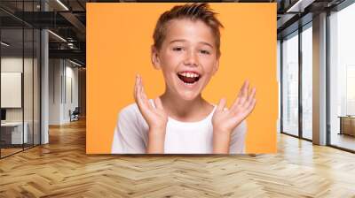 Young emotional little boy on orange studio background. Wall mural