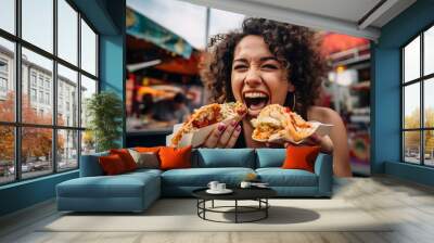 Portrait of a beautiful young woman with curly hair eating fast food outdoors. Wall mural