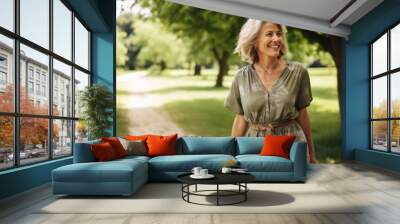 Portrait of happy senior woman walking in the park on summer day Wall mural