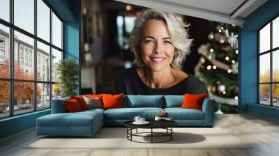 Portrait of smiling middle aged woman with christmas tree in background Wall mural