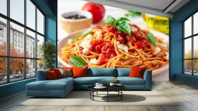 Spaghetti pasta with tomato sauce, mozzarella cheese and fresh basil in plate on white wooden background. Selective focus. Wall mural