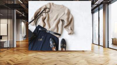 Blue midi pleated skirt, beige knitted sweater, small black cross body bag, belt, loafers (flat shoes) on grey background. Overhead view of women's casual day outfit. Flat lay, top view. Women clothes Wall mural