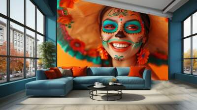 A woman smiles brightly, showcasing intricate face paint and vibrant accessories in celebration of Day of the Dead. The background is warm and festive. Wall mural